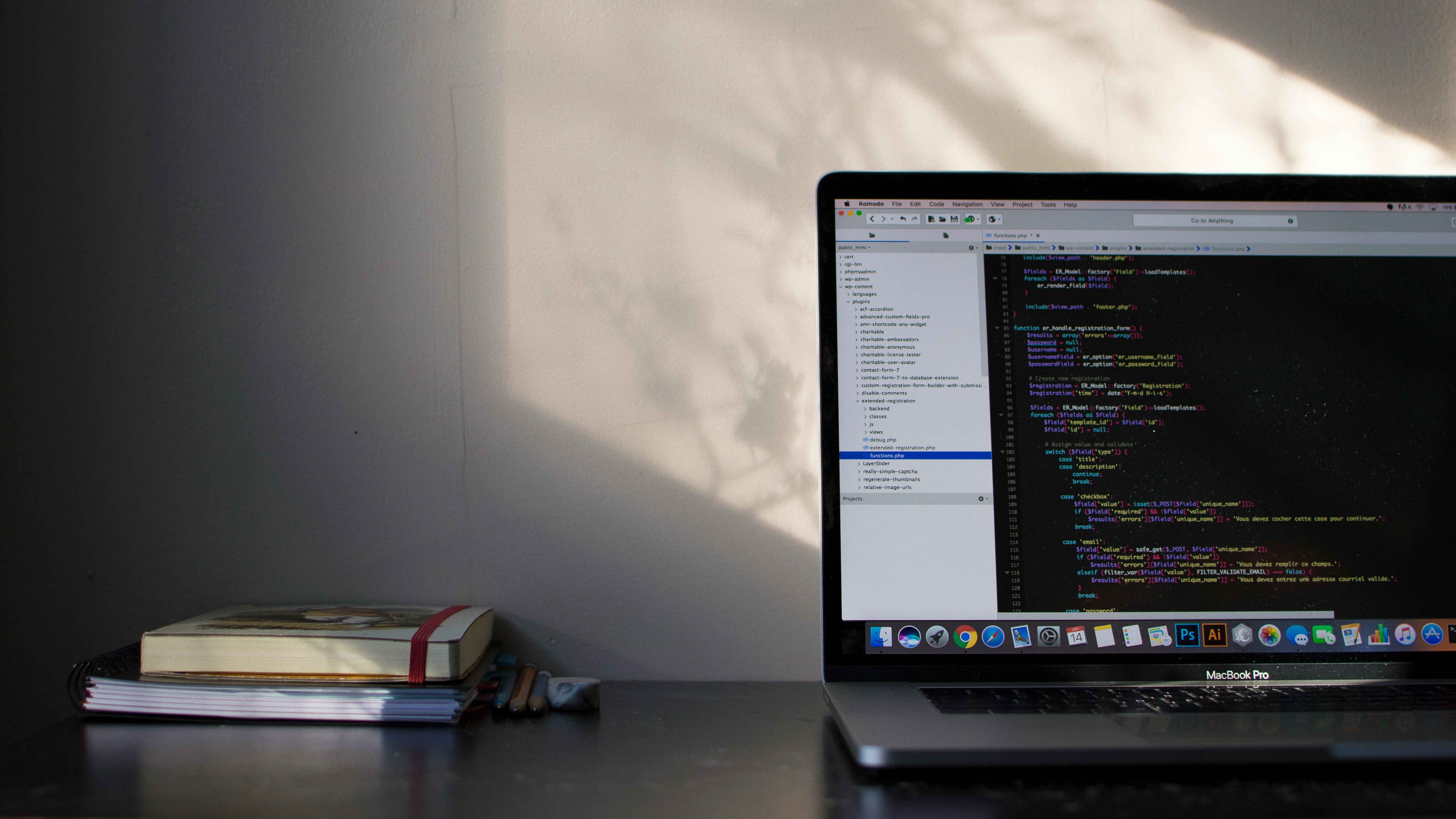 Laptop showing code beside a notebook on a desk