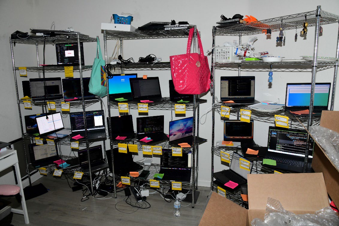 Rows of laptops on metal shelves inside a North Korean remote-worker laptop farm seized by the FBI