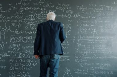 Professor studying a chalkboard covered with mathematical equations